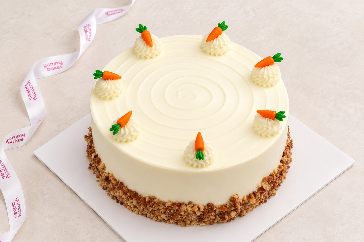Yummy Bakes Carrot Cake with cream cheese frosting, piped rosettes, carrot decorations and a crushed nut base